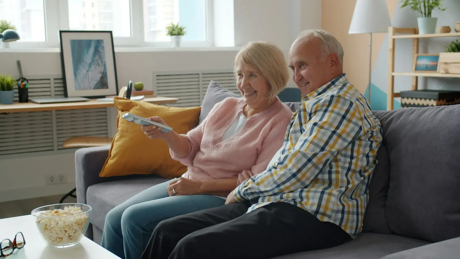 Older couple sharing popcorn in front of the TV